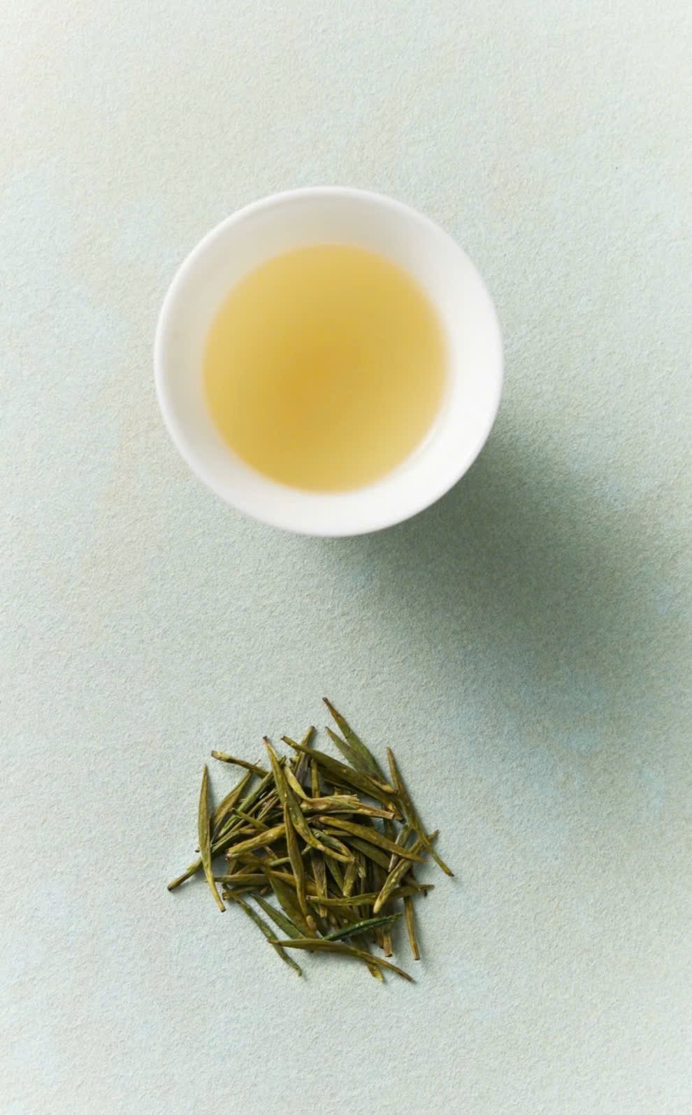 Chén trà vàng nhạt cạnh nhúm búp trà non — Suối Giàng
